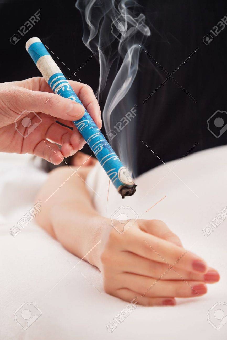 13263580-tcm-traditional-chinese-medicine-hand-applying-moxa-stick